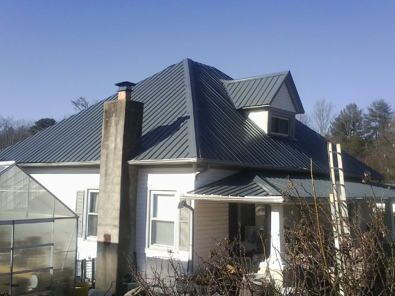 Dark blue standing seam metal roof on a white farmhouse with dormer — Slate & Tile Roof Repair by Roofing Brothers in Terre Hill