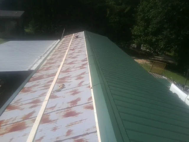 Old rusted panels beside newly installed green metal roofing — Wind Damage Roof Repair by Roofing Brothers in Terre Hill