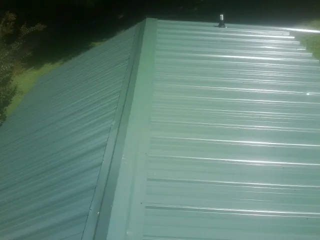 New green metal panels meeting at the ridge of a roof — Flat Roof Repair work by our crew in Terre Hill