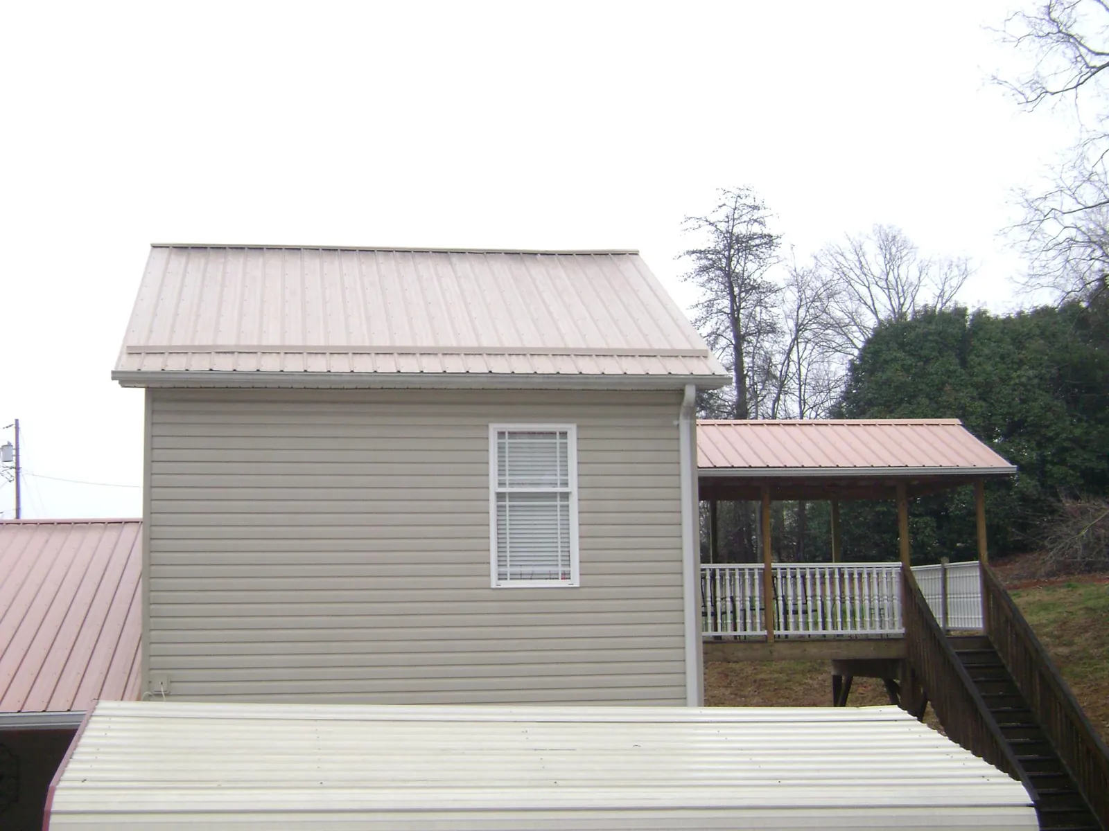 Tan metal roofs on a two story addition and attached porch, from a Roof Replacement job in Terre Hill