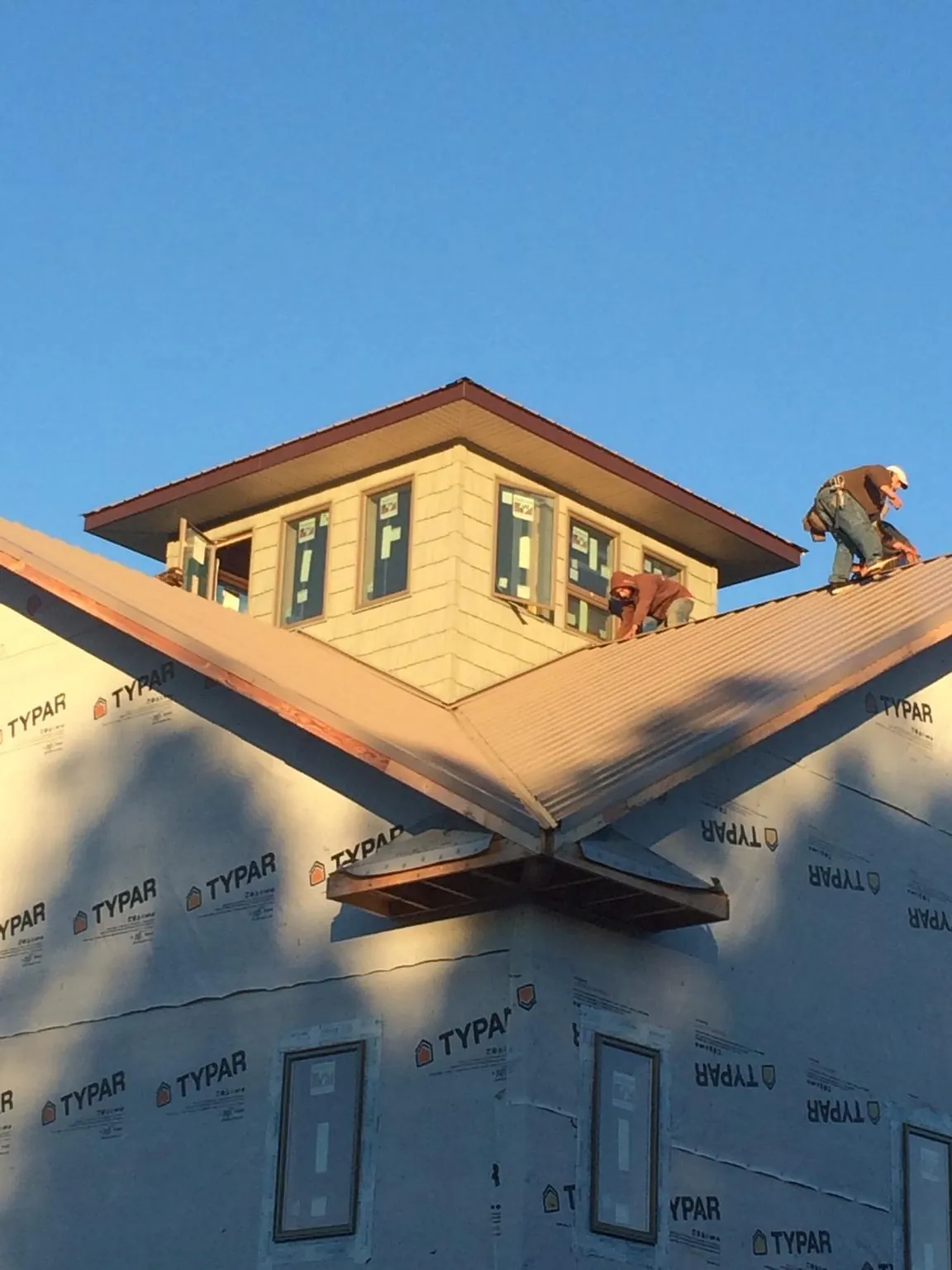 Roofers working around a rooftop cupola on a new metal roof at sunset — Roof Waterproofing in Terre Hill by Roofing Brothers